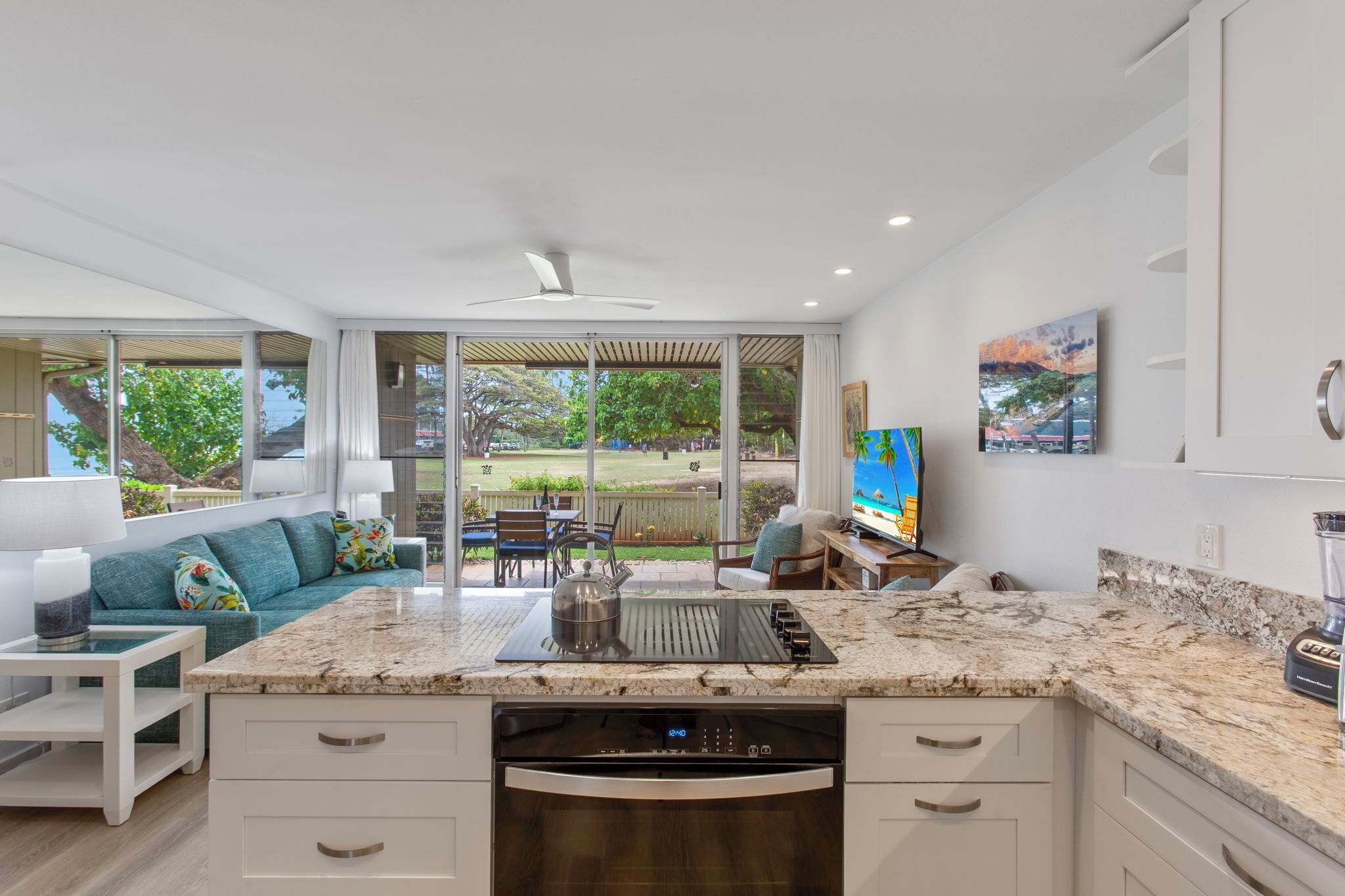 A modern kitchen with a large island, built-in appliances, and a sliding glass door leading to an outdoor patio.