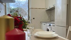 A kitchen with a wooden countertop, a washing machine, and a window with a view of trees.