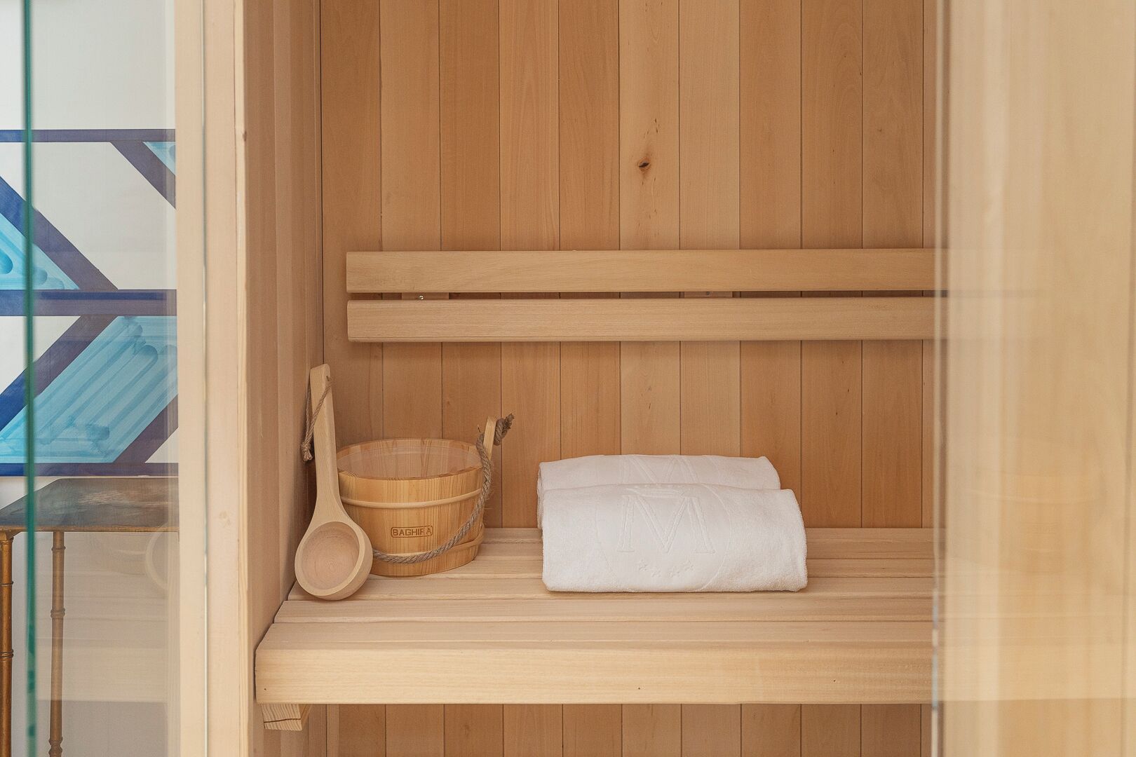 Eine Holzsauna mit einer Bank, einem Holzbecken und einem Handtuch.
