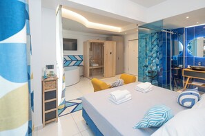 A modern hotel room with a bed, a seating area with yellow chairs, a glass-enclosed shower area, and a wooden wardrobe. - Maiori Suites (Maiori)