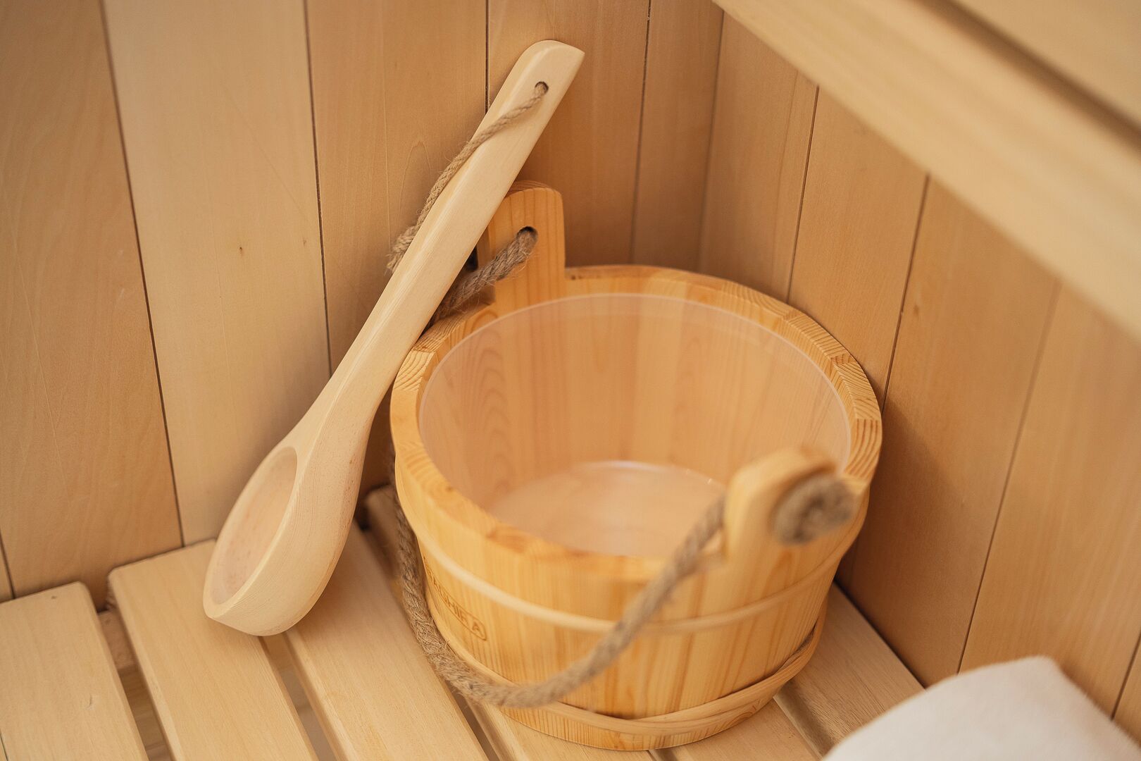 A wooden bathtub with a wooden ladle and a wooden bucket inside a wooden room.
