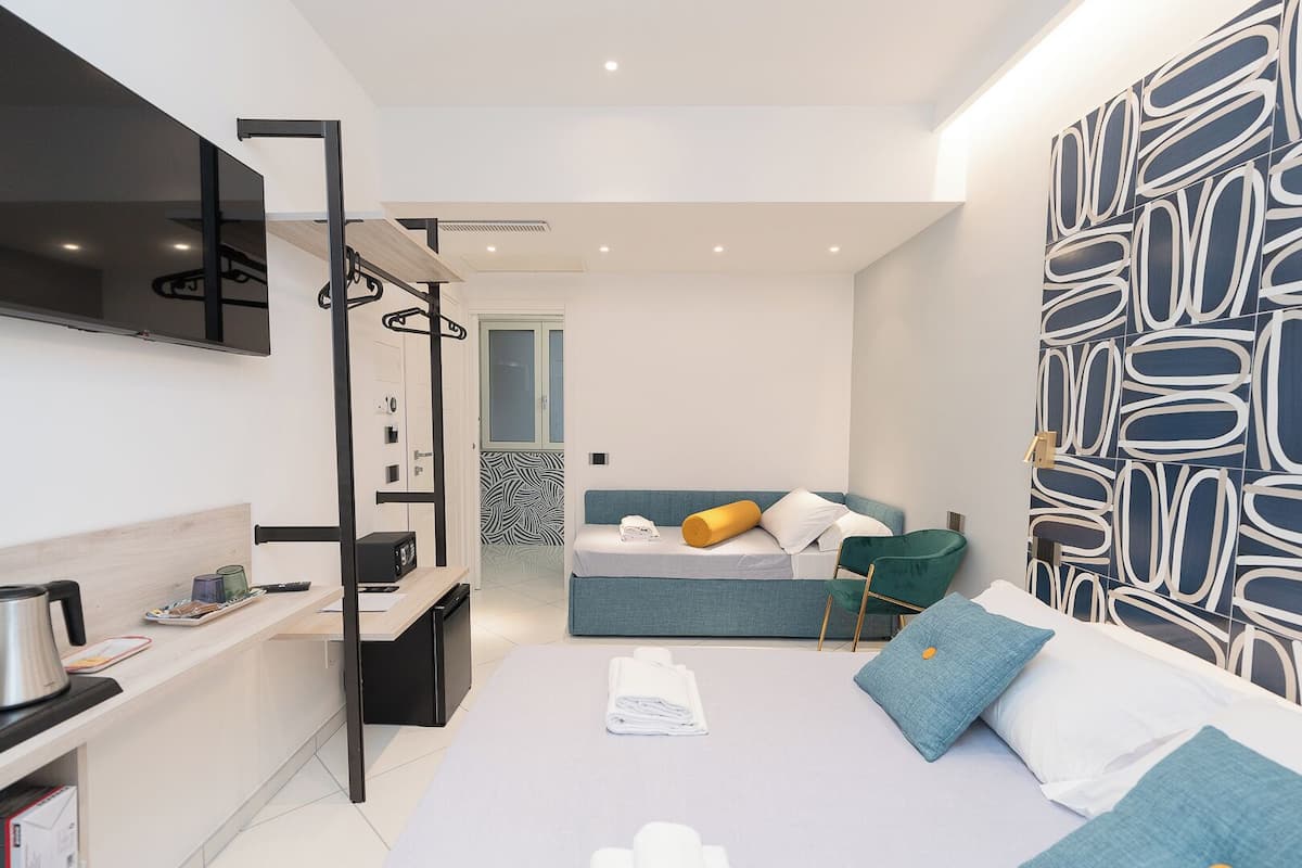 A modern bedroom with a bed, a desk, a chair, and a TV mounted on the wall.