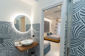 A modern bathroom with a round mirror, a wooden vanity, and patterned wallpaper. - Maiori Suites (Maiori)