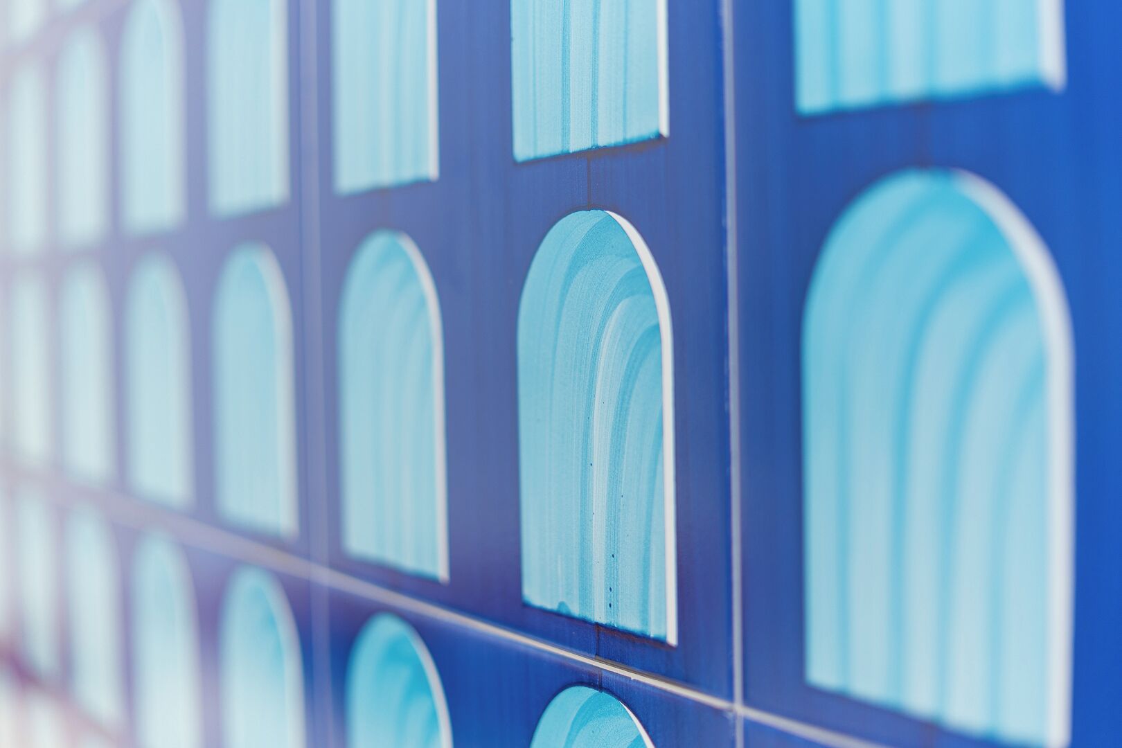 Primer plano de una pared azul con varios ventanales de arco.