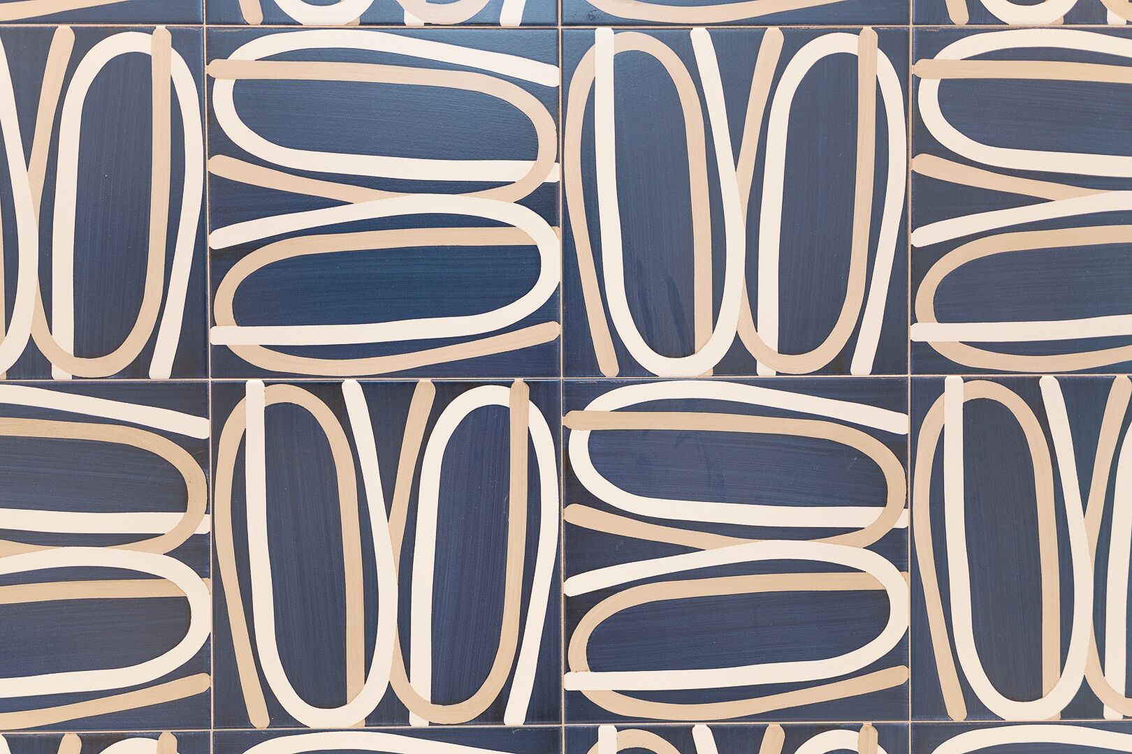 A tiled wall with a repeating pattern of abstract shapes in blue and beige.