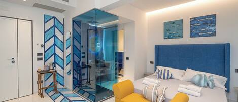 Een moderne slaapkamer met een groot bed, een gele fauteuil en een glazen scheiding.