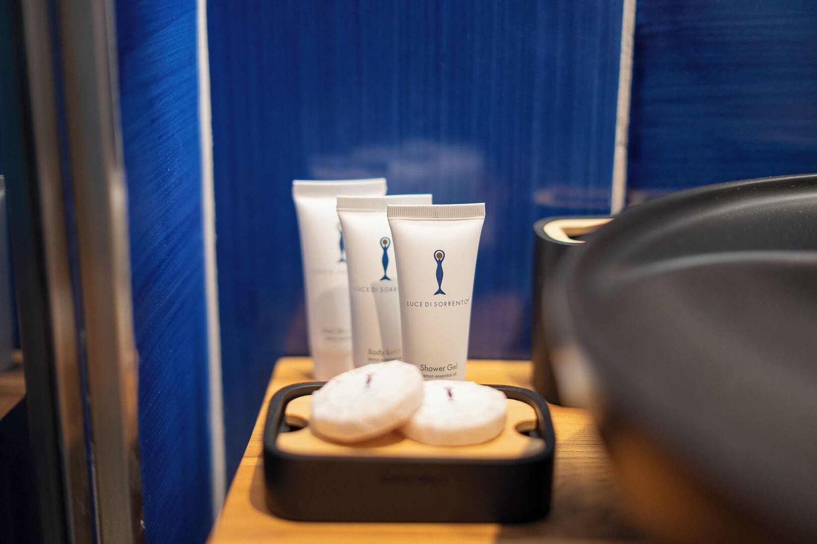 A bathroom with toiletries on a shelf, including body lotion and shower gel.