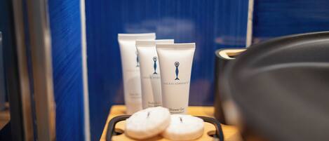 A bathroom with toiletries on a shelf, including body lotion and shower gel.