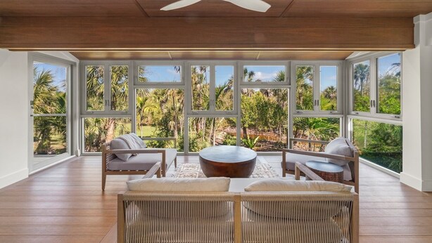 A spacious room with large windows, a ceiling fan, and a wooden floor.