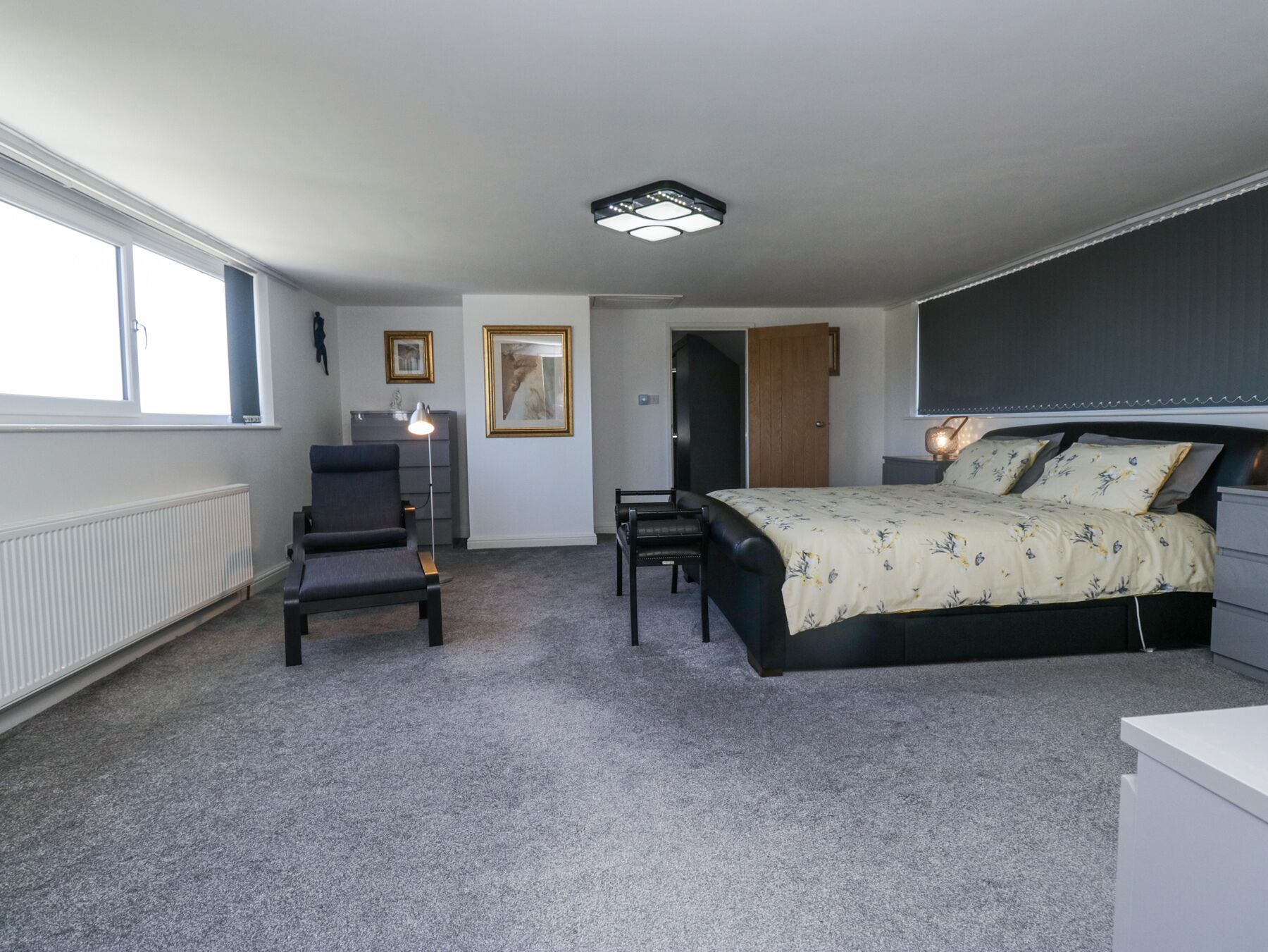 A bedroom with a bed, a desk, a chair, a radiator, and a window.