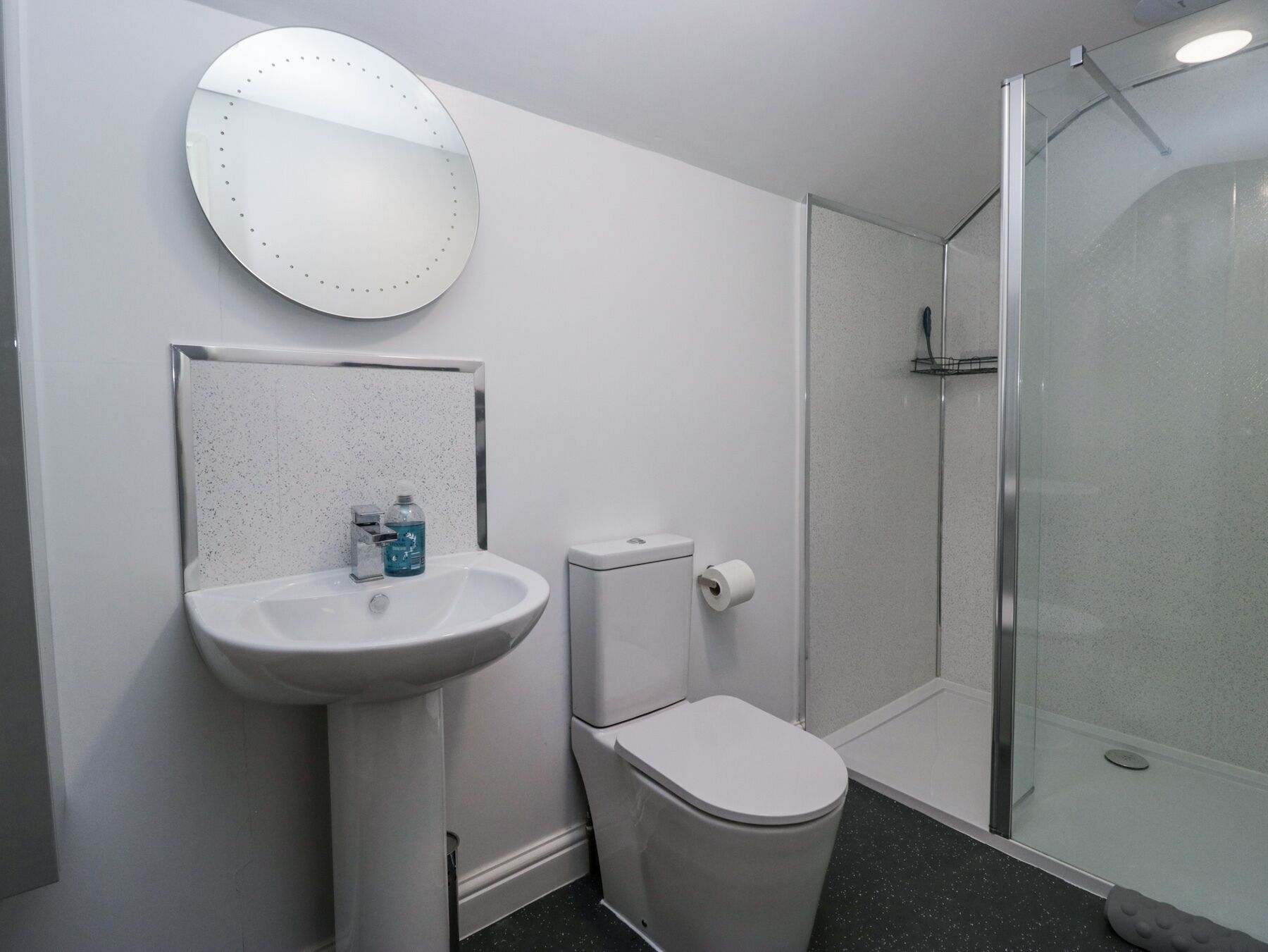 A bathroom with a white sink, toilet, and glass shower enclosure.