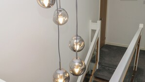 Un escalier doté d’une rampe en verre et d’une série de luminaires sphériques suspendus.