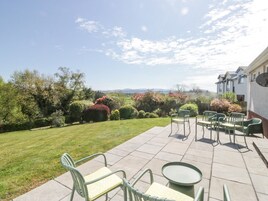 A patio with outdoor furniture, a well-maintained lawn, and a view of a residential area with houses and trees.