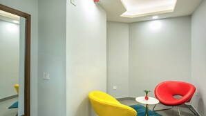 Una habitación moderna con un espejo, dos sillas, una mesita y una alfombra azul.