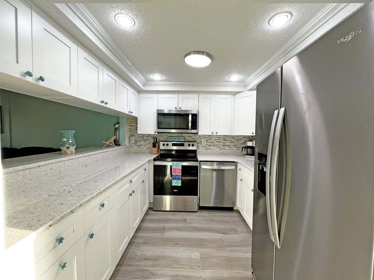 A modern kitchen with white cabinets, stainless steel appliances, and a tiled backsplash.