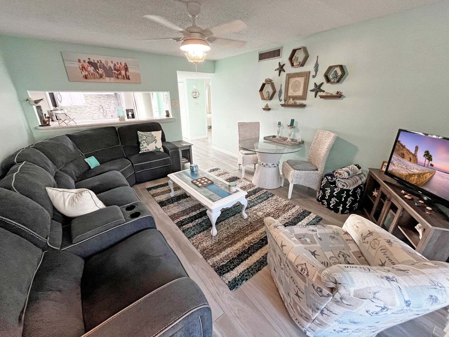 A living room with a sofa, armchairs, a coffee table, and a television.