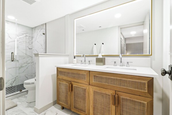 A modern bathroom with a white vanity, a large mirror, and a glass shower enclosure.