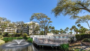A hotel with a pool area, surrounded by palm trees and a water feature.