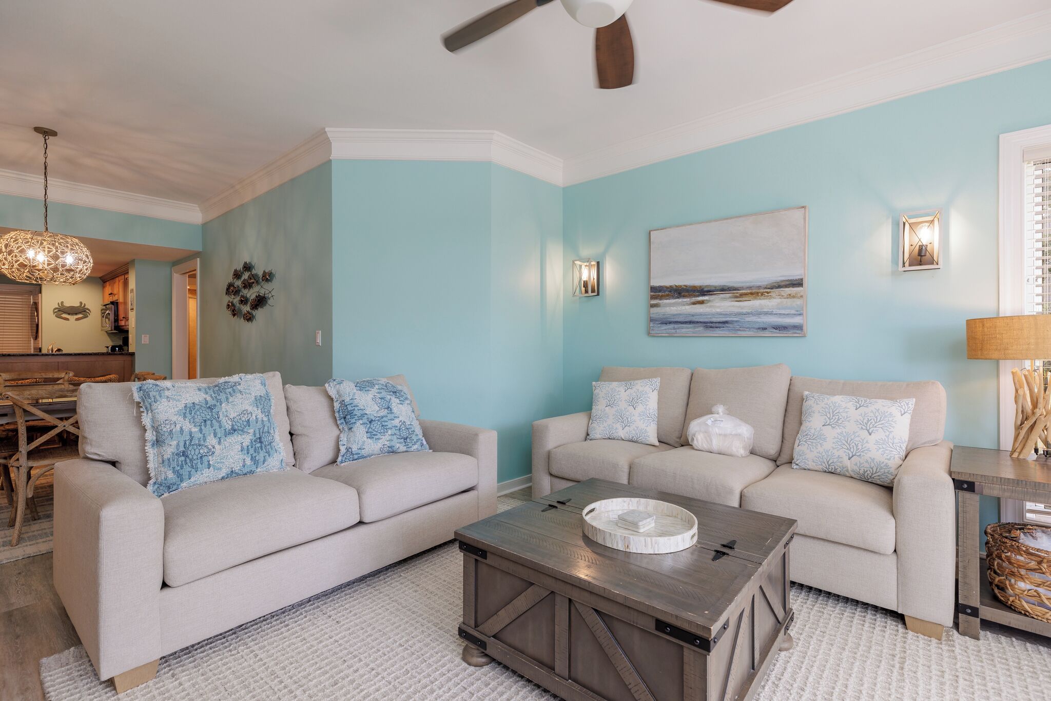 A living room with two sofas, a coffee table, a ceiling fan, and a painting on the wall.
