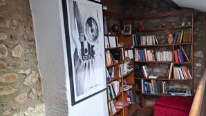 A cozy reading nook with a wooden bookshelf, a red ottoman, and a map on a wooden cabinet.