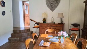 A dining area with a wooden table, chairs, a decorative wall piece, and a staircase leading to another room.