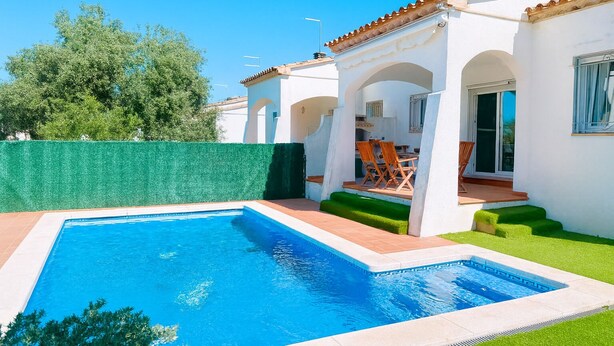 A swimming pool with a tiled deck, a patio with outdoor furniture, and a white building with arches and a tiled roof. - Villa with private Pool/Aircon/Wi-Fi - Villa Montgrí (L'Escala)