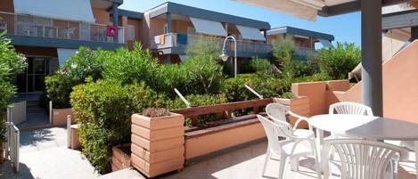 A rooftop terrace with outdoor seating, a water fountain, and a view of adjacent buildings.