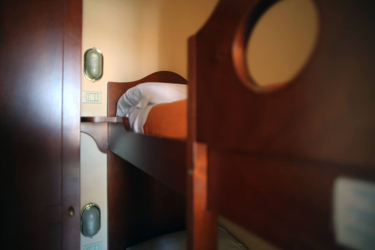 A bunk bed in a room with a wooden door and a mirror on the wall.