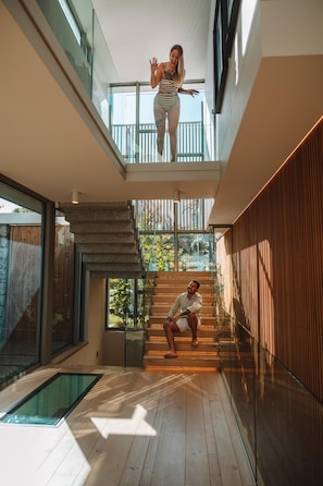 Ein modernes Interieur mit einer gläsernen Treppe, einem Pool und einem Balkon.