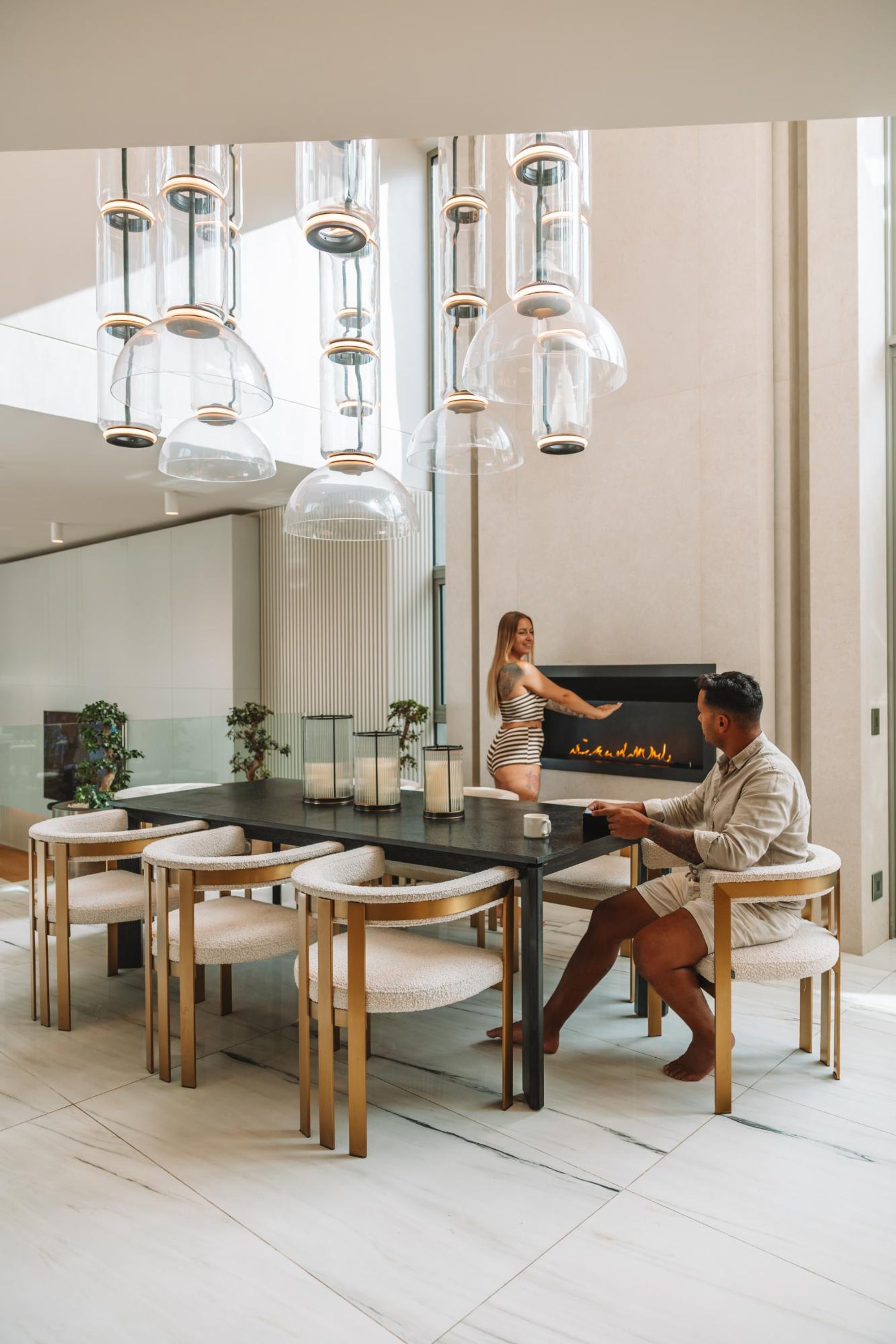 Un espace de salle à manger moderne, doté d’une grande table, de plusieurs chaises et d’un éclairage suspendu.