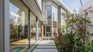 A modern building with large glass windows, a narrow pathway, and lush greenery. - Grand Camps Bay 5bed w Views Pool Gym Villa Serena (Cape Town)