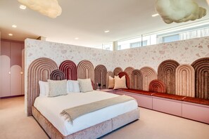 A modern bedroom with a large bed, a bench, and a unique wall design. - Grand Camps Bay 5bed w Views Pool Gym Villa Serena (Cape Town)