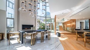 A modern hotel lobby with a pool table, seating area, and a staircase leading to upper floors. - Grand Camps Bay 5bed w Views Pool Gym Villa Serena (Cape Town)