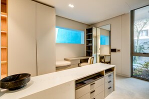 A modern bathroom with a large mirror, a white vanity, and a black basin.