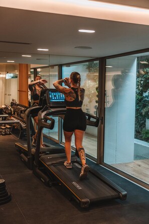 A gym with treadmills, weights, and a large window.