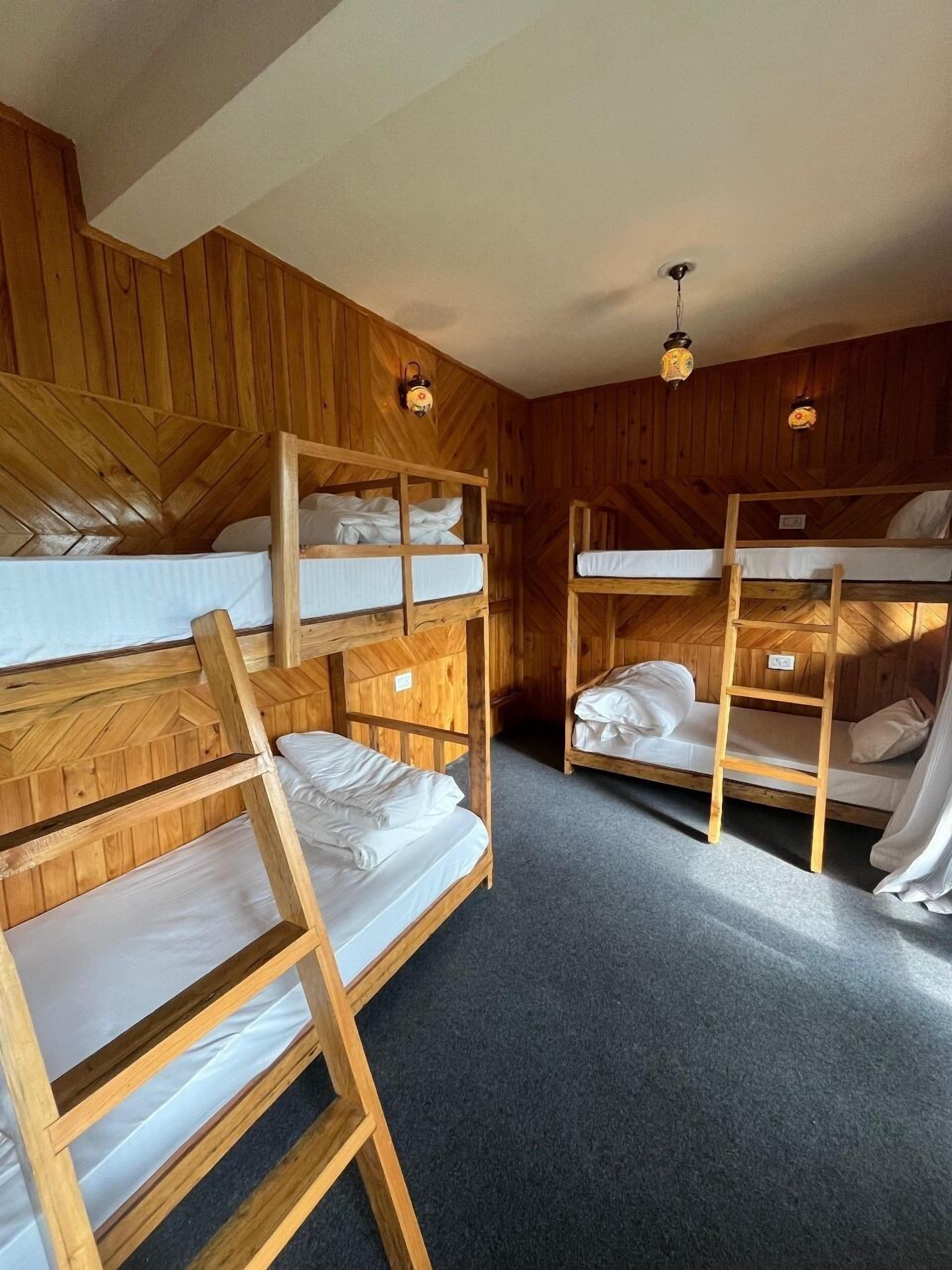 A bunk bed room with wooden walls and two hanging light fixtures.