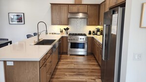 A modern kitchen with wooden cabinets, stainless steel appliances, and a central island. - Snowcreek Resort Vacation Rental 1555 (Mammoth Lakes)