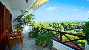 A balcony with a wooden bench, potted plants, and a view of a green landscape. - Elani Private Retreat - Villa Anna Garden Escape (Kassandra)