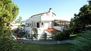 A white villa with a tiled roof, surrounded by lush greenery and a well-maintained lawn. - Elani Private Retreat - Villa Anna Garden Escape (Kassandra)