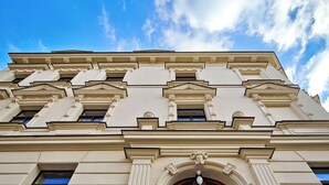 A classical building facade with a symmetrical design, featuring a central arched doorway and a set of double doors.
