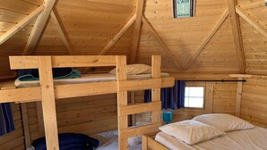 Una cabaña de madera con literas, una ventana con cortinas y un cartel en la pared.