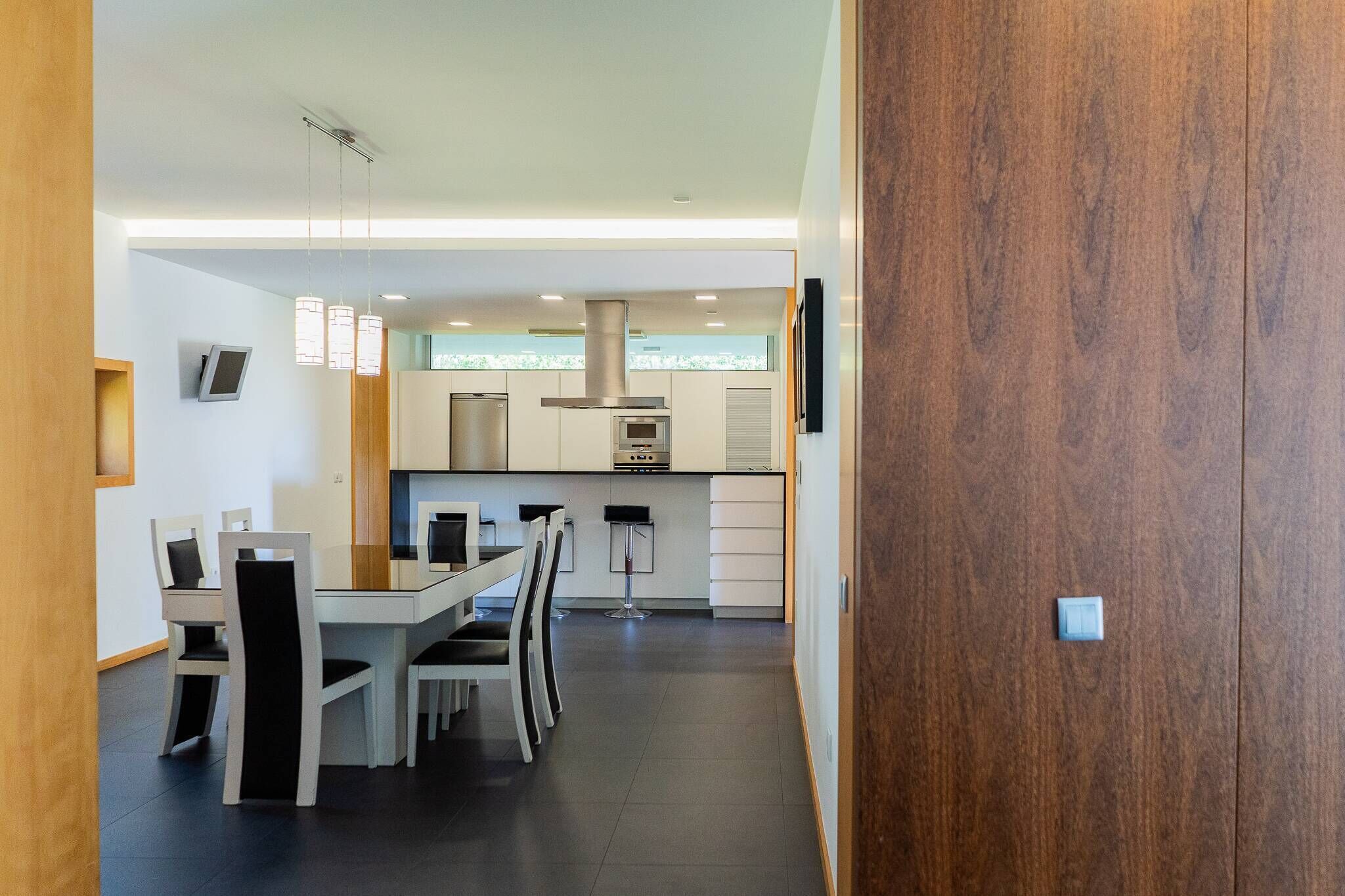 A modern kitchen with white cabinets, stainless steel appliances, and a dining area with a white table and chairs.