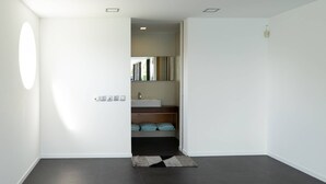 Een strakke badkamer met een donkere vloer, witte wanden, een wit wastafelmeubel en een spiegel.