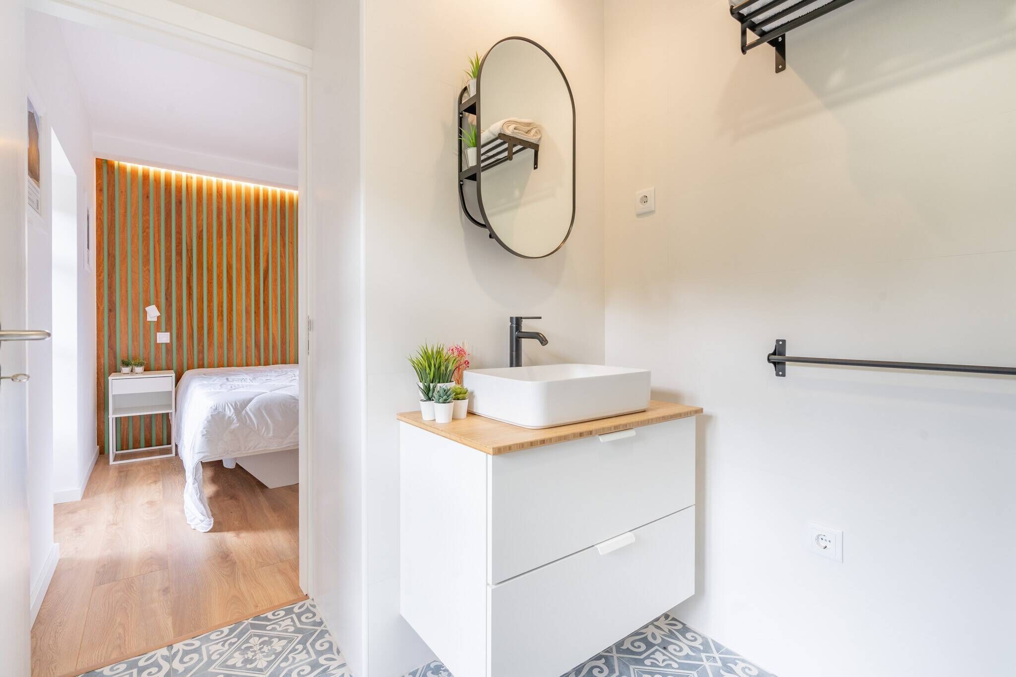 A modern bathroom with a white vanity, a large mirror, and a wooden floor.