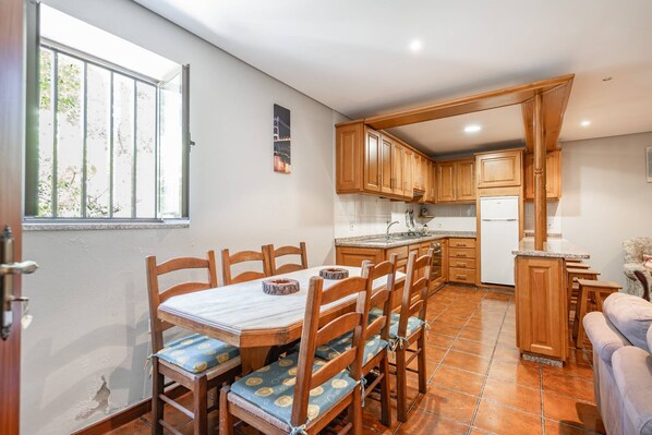 A kitchen with wooden cabinets, a dining table with chairs, and a refrigerator.