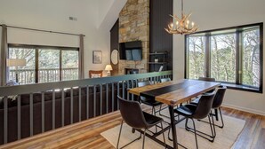 Un coin repas agrémenté d’une cheminée en pierre, d’un téléviseur et offrant une vue sur l’extérieur.