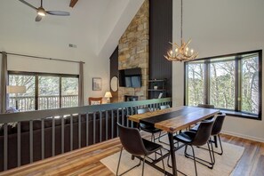 A dining area with a stone fireplace, a television, and a view of the outdoors.