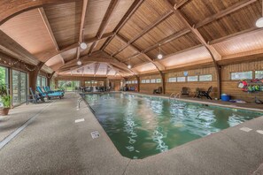 An indoor swimming pool with wooden walls and ceiling, surrounded by lounge chairs and tables. - Condo 3B/3BA + Amenity Pass w/ Hot Tub + Pool. (Blowing Rock)