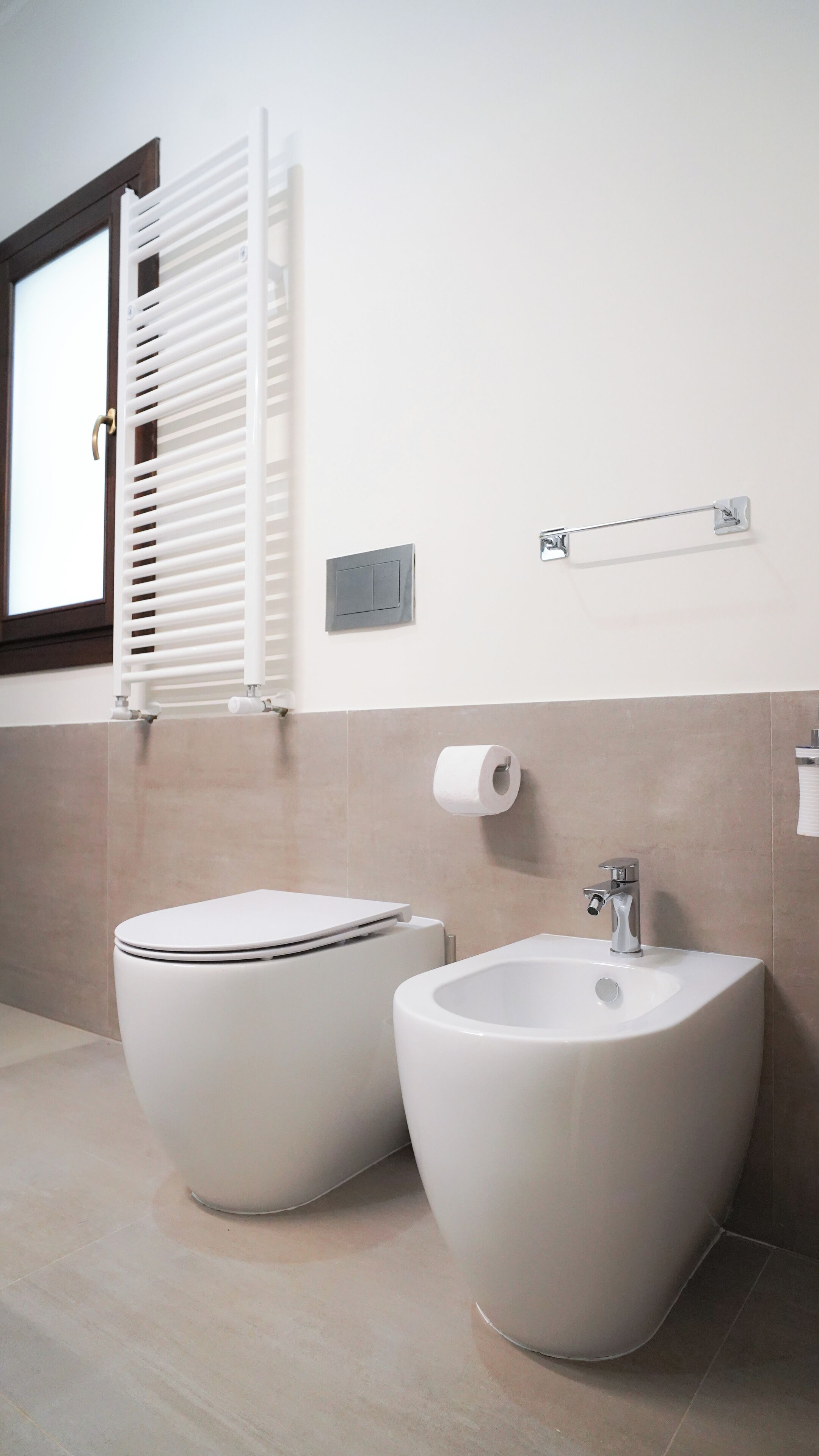 Een moderne badkamer met toilet, hygiëneschuimer en een handdoekrek.