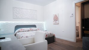 Ein modernes Schlafzimmer mit einem weißen Ziegelkopfteil, einer floralen Tagesdecke und einem kleinen Schreibtisch mit Stuhl.